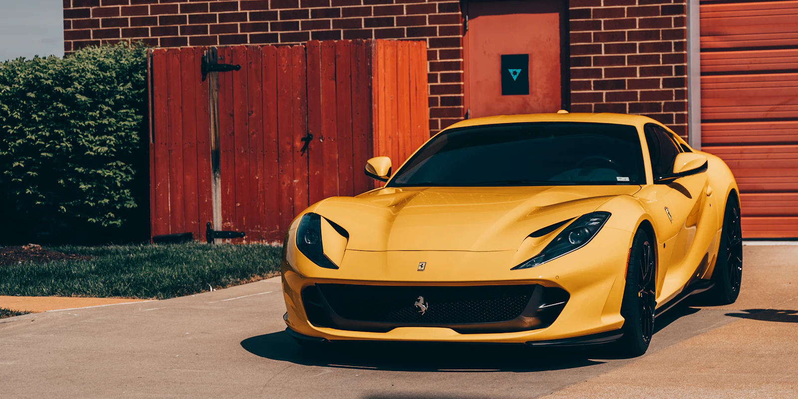 Yellow Ferrari 812 Superfast by a brick building